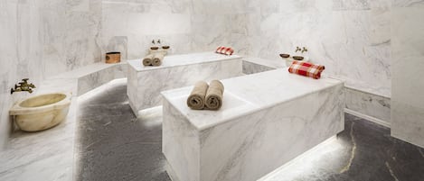 A modern bathroom with marble countertops, a bathtub, and a toilet.