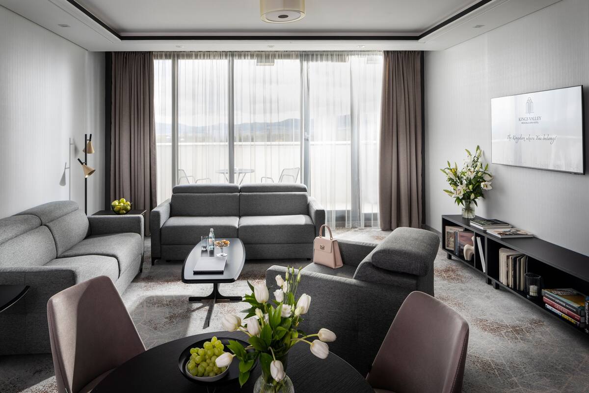 A modern living room with grey sofas, a coffee table, and a bookshelf.