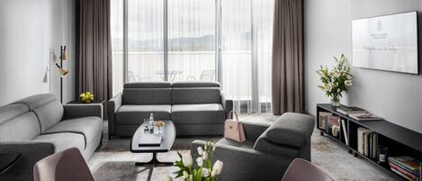 A modern living room with grey sofas, a coffee table, and a bookshelf.