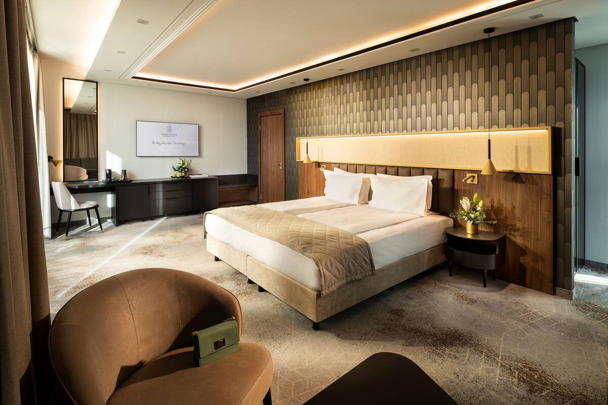 A modern hotel room with a large bed, a desk, and a chair.
