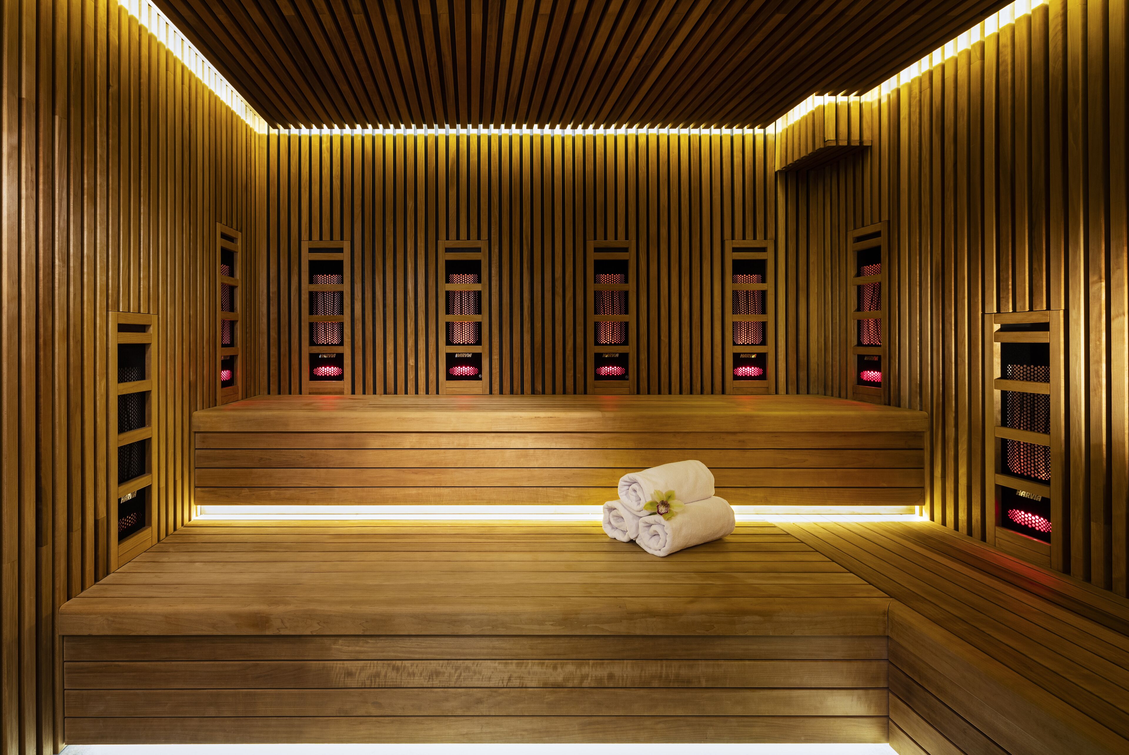 Eine Sauna mit Holzwänden und -bänken, ein Handtuch liegt auf dem Boden.