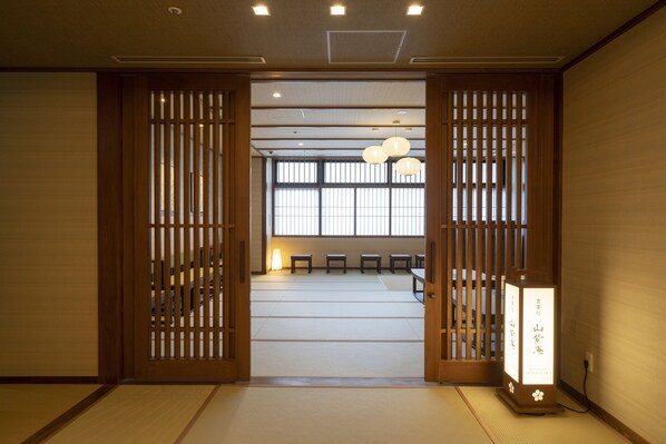 Una habitación japonesa tradicional con suelo de tatami, puertas correderas y un mampara de shoji.