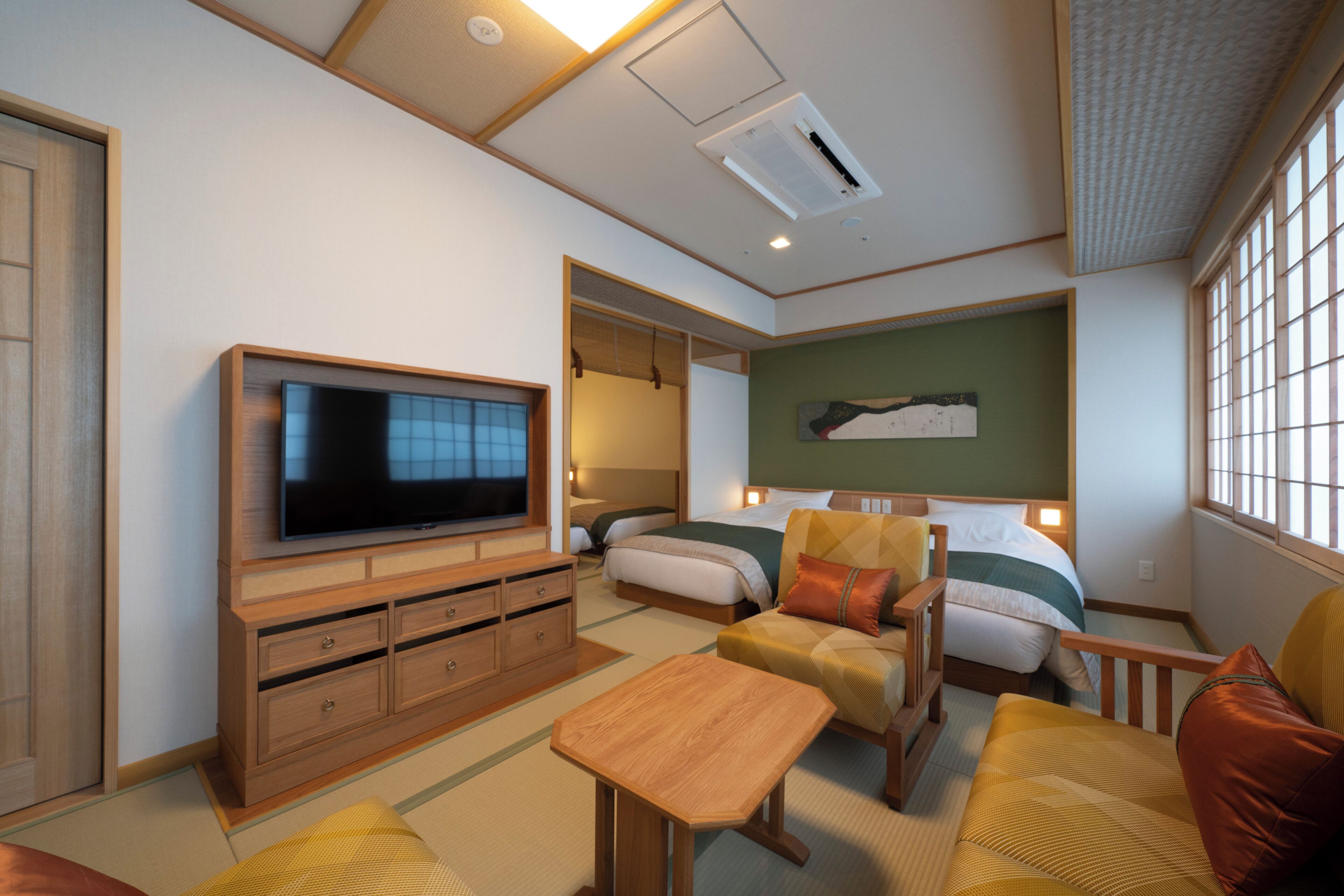 A hotel room with a television, a bed, a sofa, a wooden cabinet, and a window.