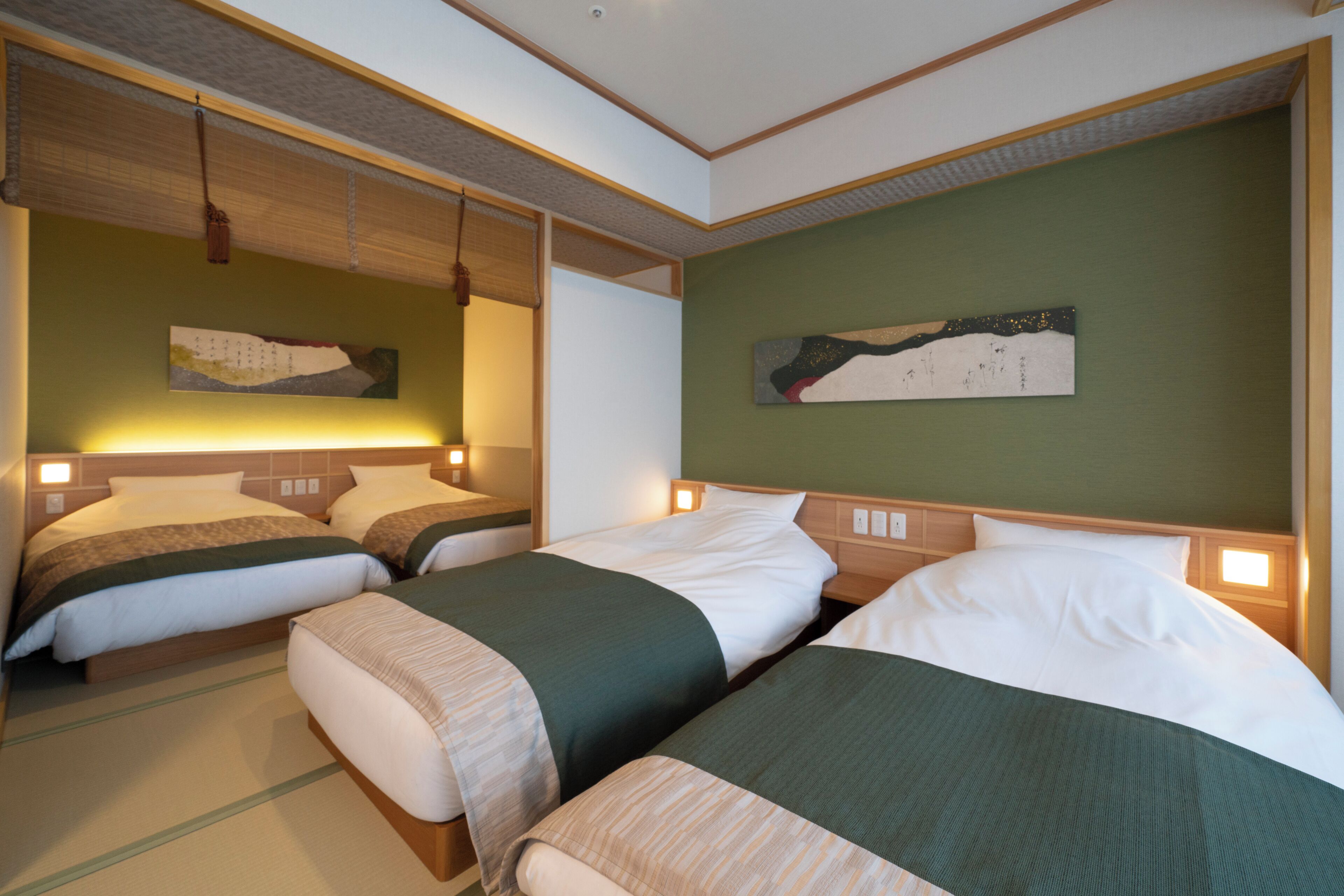 Una habitación de hotel con dos camas, una pared verde y obras de arte.