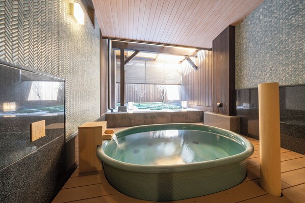 Un área de spa con un jacuzzi grande, paredes de madera y vistas a un jardín.
