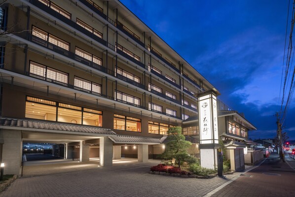 Un hotel de varios pisos con ventanas iluminadas y una entrada tradicional.
