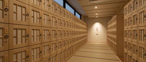 A row of wooden lockers with numbers on them, arranged in a hallway with a tiled floor.
