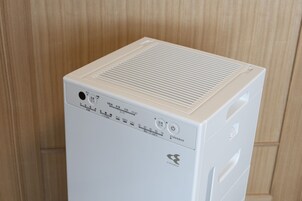 A white, compact, modern appliance with a control panel featuring various settings and a power button.