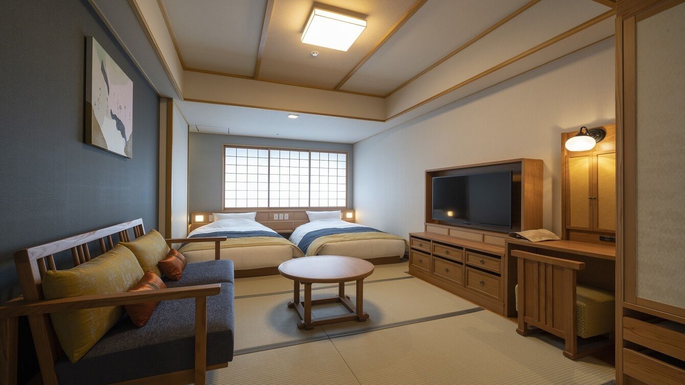 Una habitación de hotel con sofá, dos camas, televisión, armario y ventana.