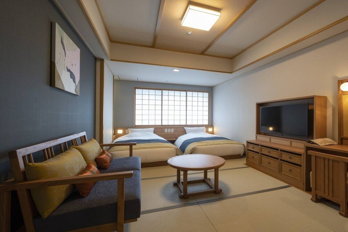 A hotel room with a sofa, two beds, a TV, a cabinet, and a window.