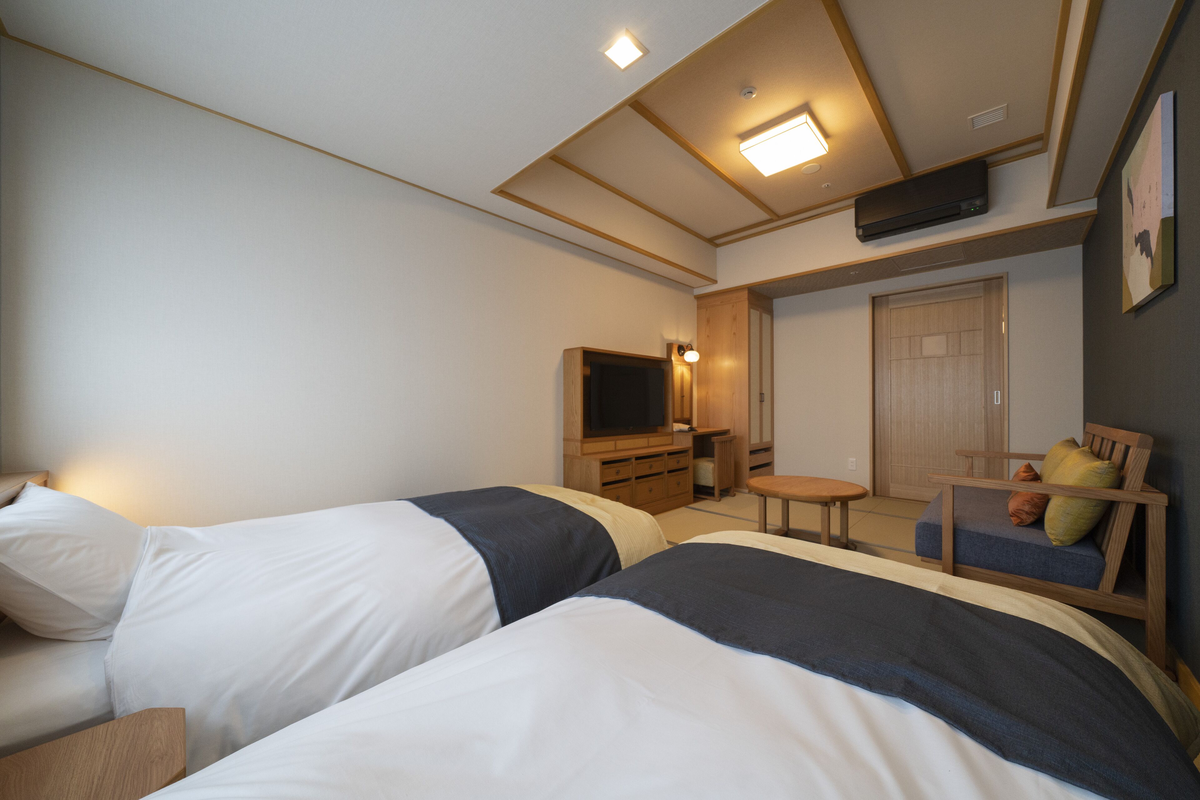 Una habitación de hotel con dos camas, televisión, una mesita y una zona de estar.