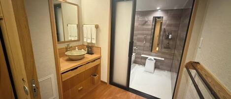 A modern bathroom with a wooden vanity, a large mirror, and a glass shower enclosure.