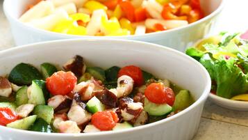 Trois bols de salade contenant divers légumes et une assiette de crudités.