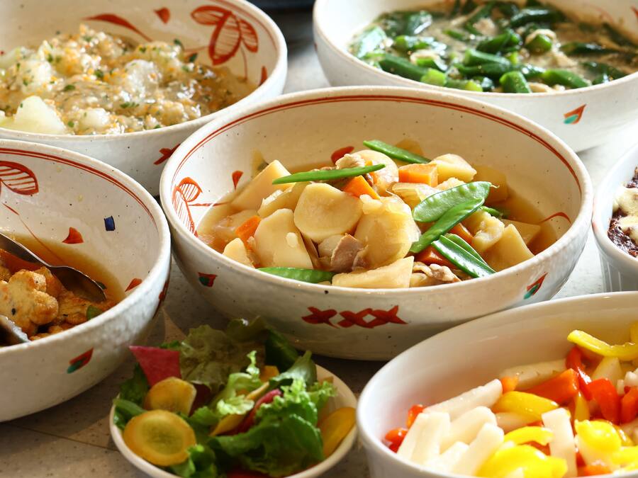 A variety of dishes in bowls, including vegetables and possibly meat, arranged on a table.