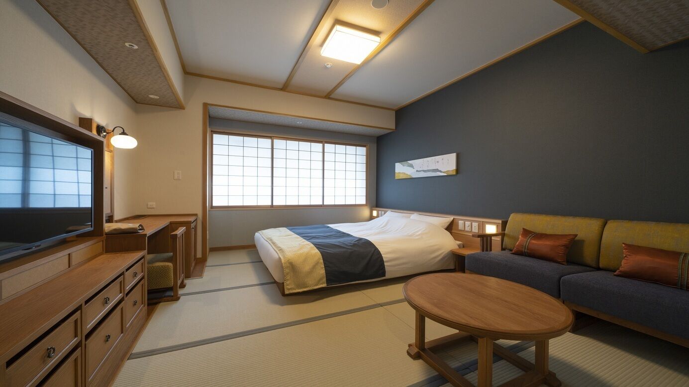 Una habitación de hotel con cama, sofá, televisor, escritorio y ventana.