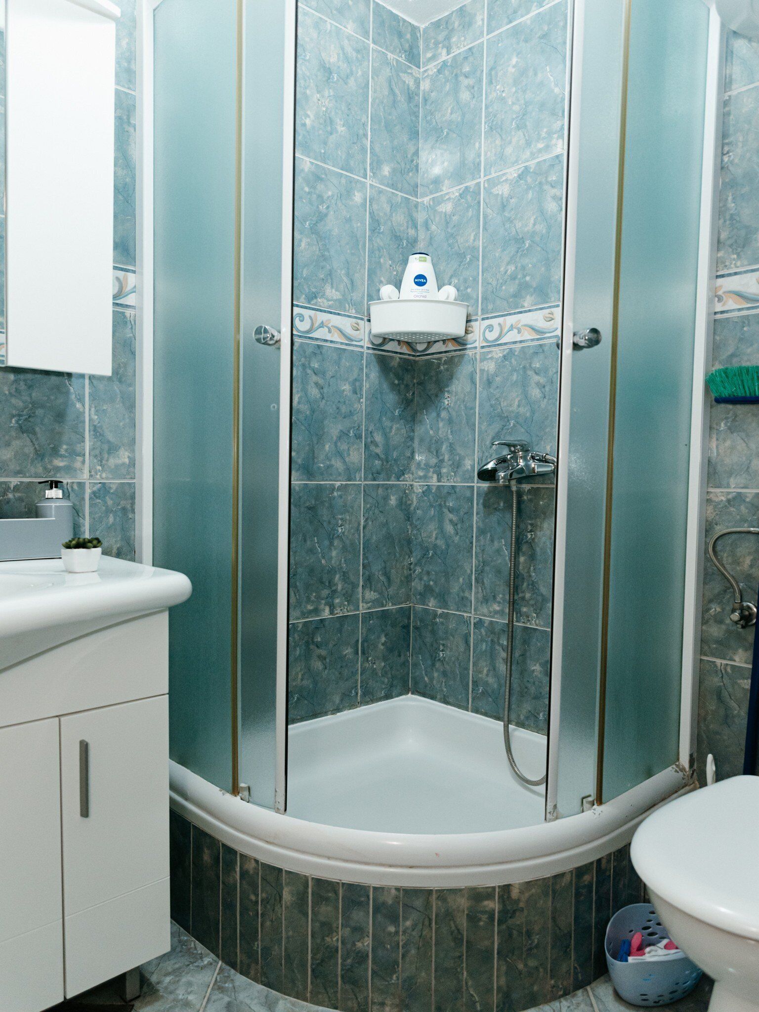 A bathroom with a shower enclosure, a sink, and a toilet.