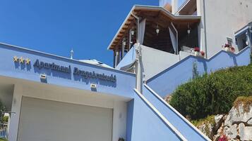A building with a sign reading 'Apartmani Dragobratovici' and a white garage door.