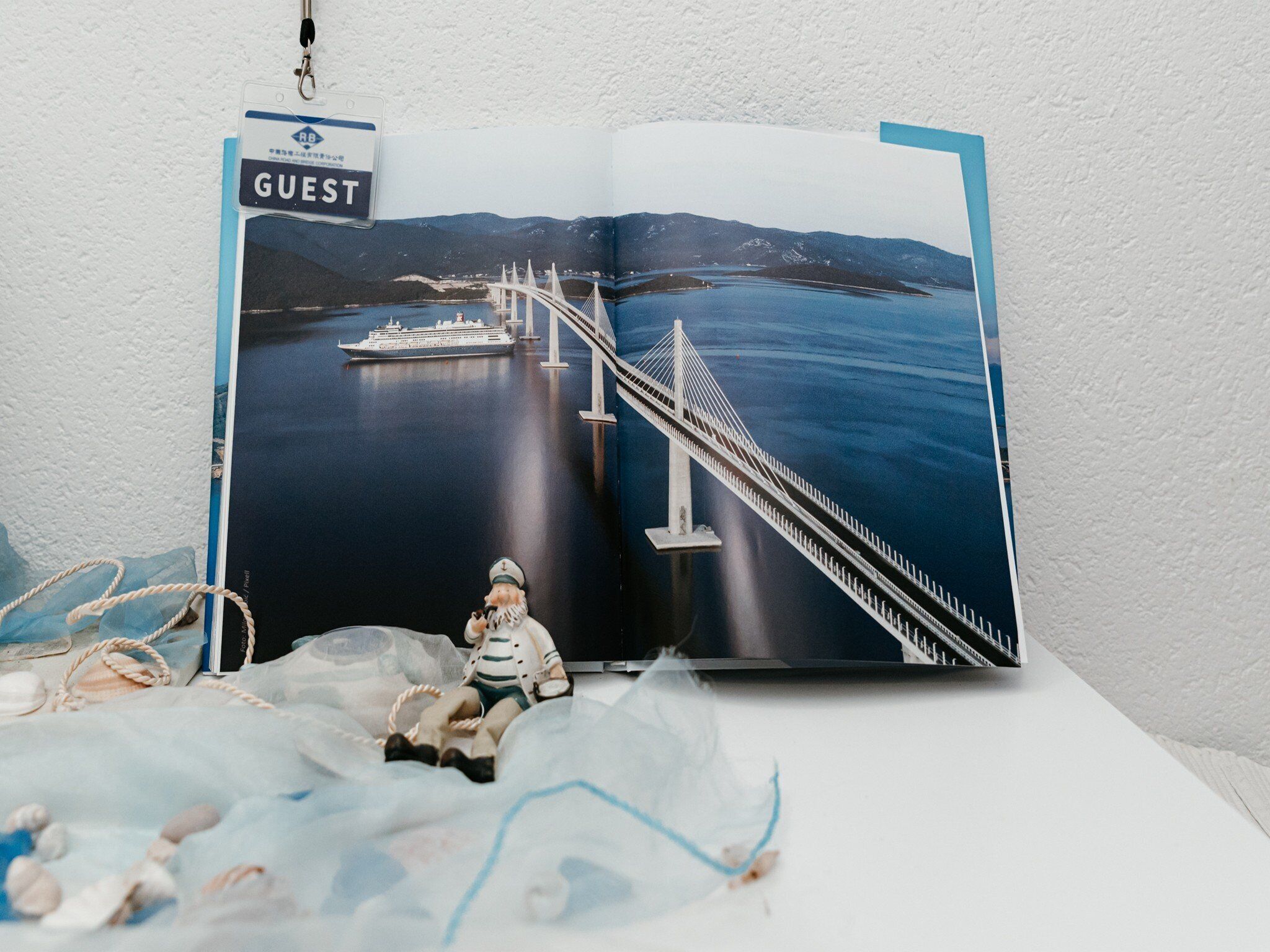 A book with a photograph of a bridge over water, a ship, and a figurine of a person.
