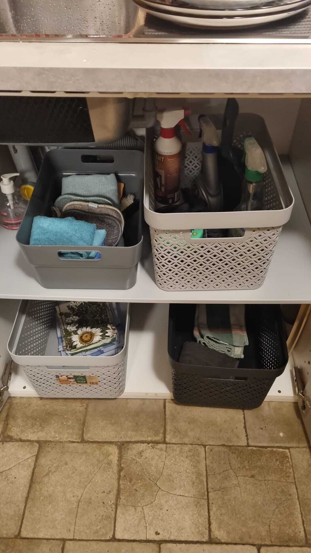 A kitchen shelf with storage baskets containing kitchen utensils, a bottle of dish soap, and a blue cloth.