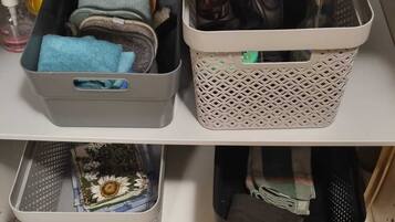 A kitchen shelf with storage baskets containing kitchen utensils, a bottle of dish soap, and a blue cloth.