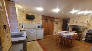 A compact kitchen with a stone wall, wooden cabinets, and a dining area with a table and chairs.