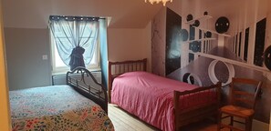 A bedroom with a bed, a chair, a window with curtains, and a wall mural. - Chez Émile Logement Entier, 2 Chambres, Jardin Privé (Hûmes)