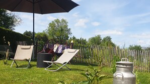 A backyard with two lounge chairs, a table with a tablecloth, a metal fire hydrant, and a wooden fence.