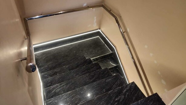 A set of black marble stairs with a metal handrail, leading to a landing. - The Republic Hotel (Ambala)