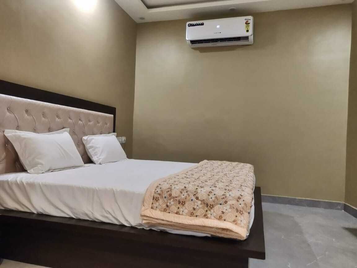 A neatly made bed with a patterned blanket, a headboard, and a wall-mounted air conditioner.