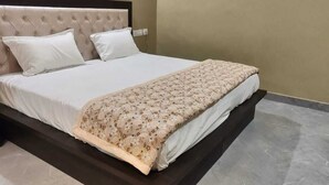 A bed with a tufted headboard, white bedding, and a floral-patterned blanket. - The Republic Hotel (Ambala)