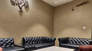 A room with black leather sofas and a white table. - The Republic Hotel (Ambala)