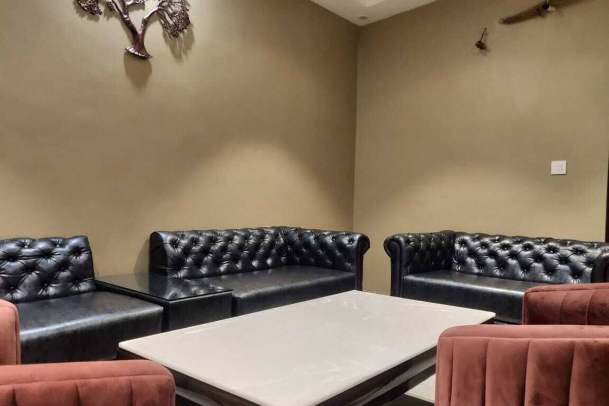 A room with black leather sofas and a white table.