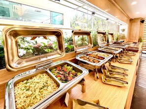 A buffet with multiple food stations, including rice, pasta, and salads.