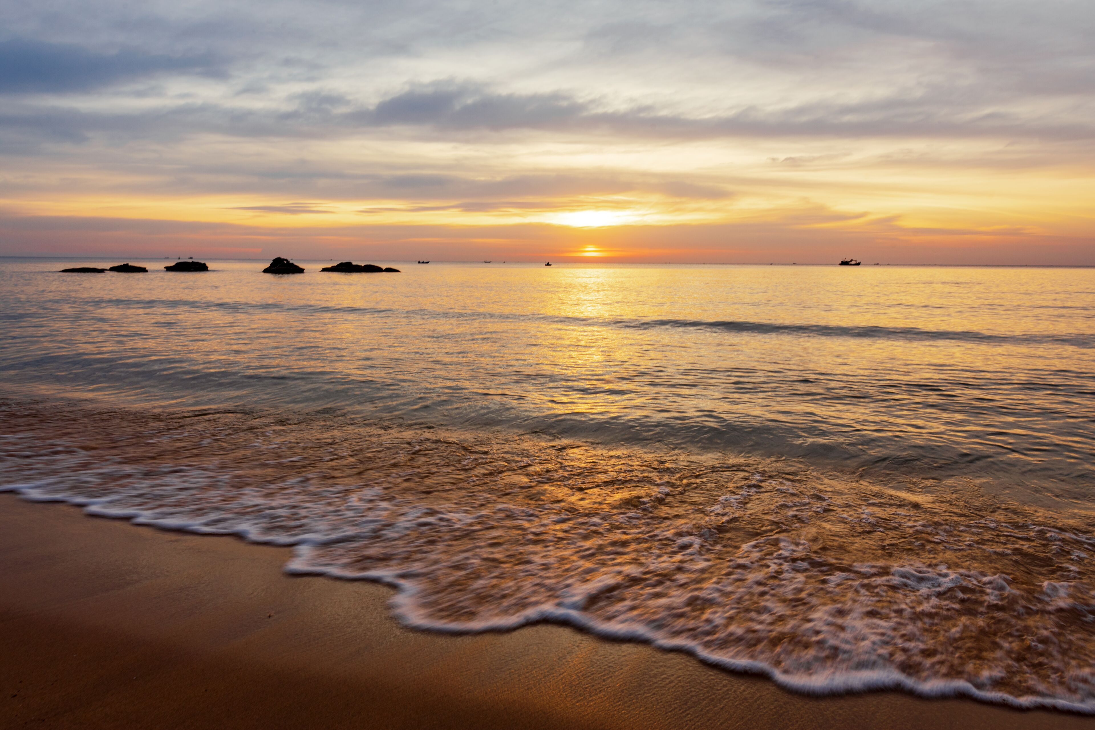 A beach with waves at sunset.
