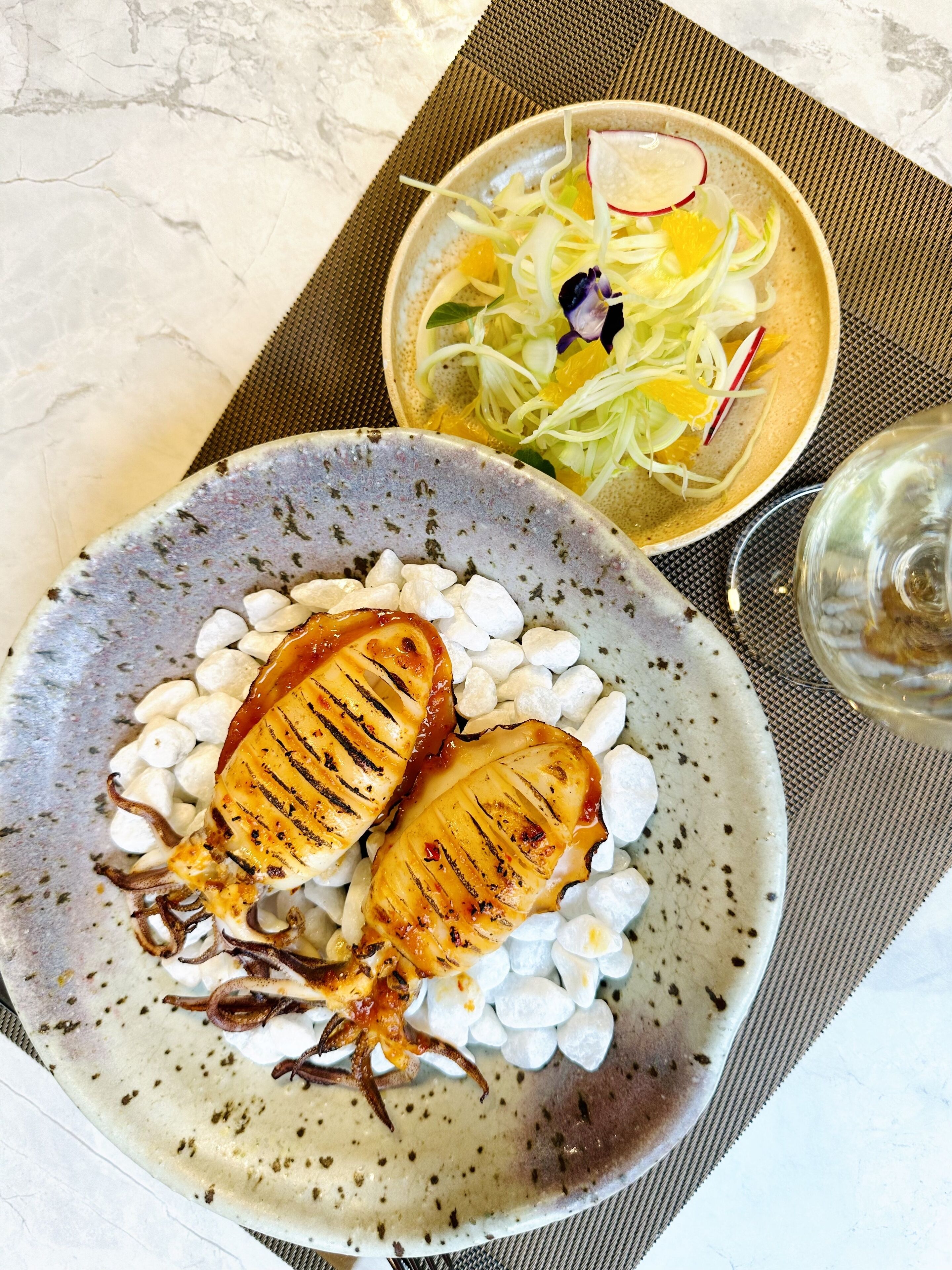 A plate of grilled fish with white beans and a side salad.