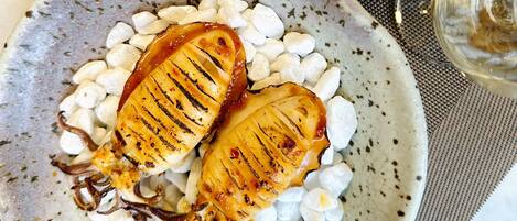 A plate of grilled fish with white beans and a side salad.