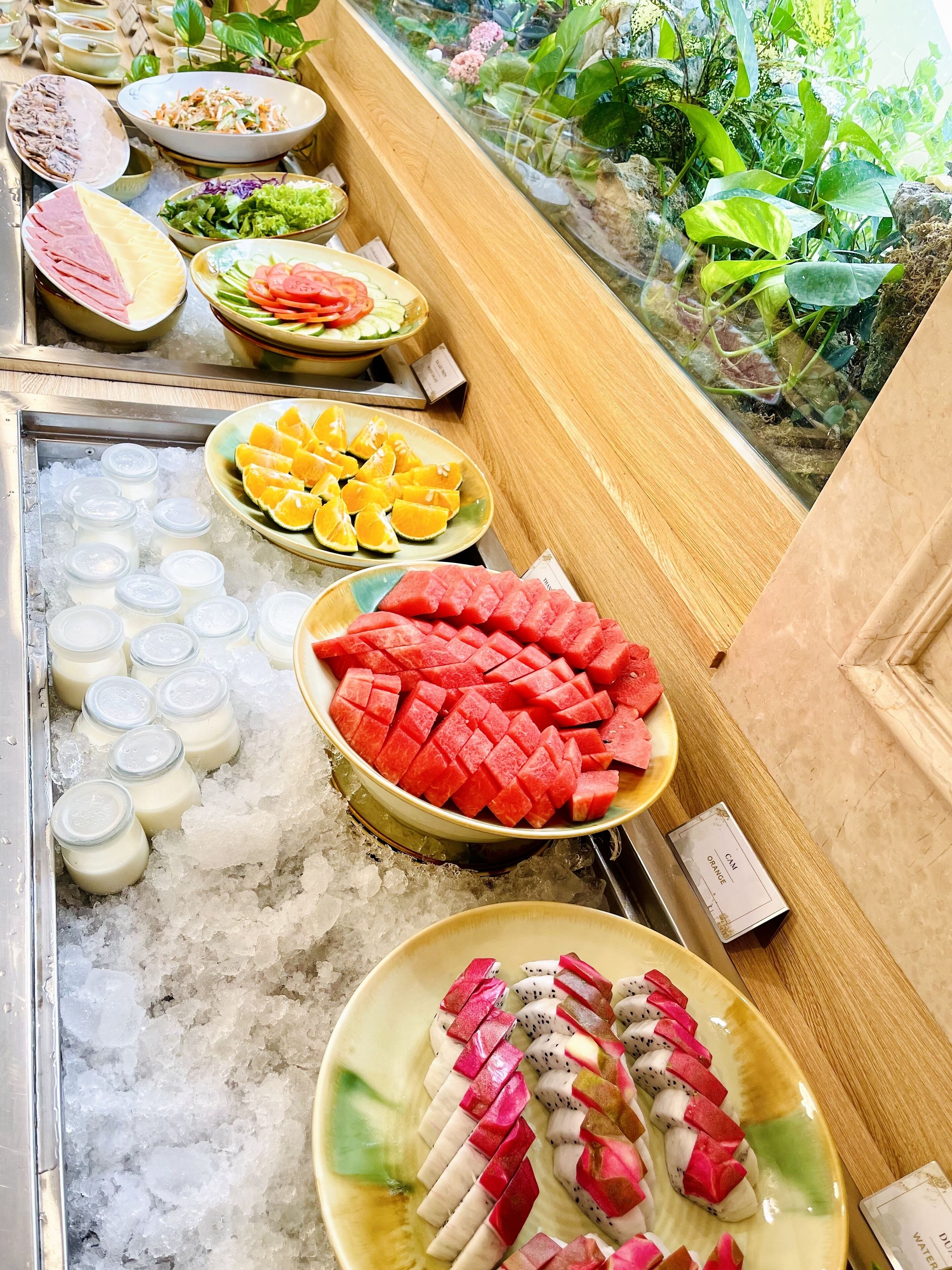 Une variété d’aliments, notamment des pastèques, des oranges et d’autres fruits, sont présentés sur de la glace dans un restaurant.