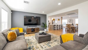Una sala de estar moderna con un televisor de pantalla plana, sofás grises y una mesa de centro.