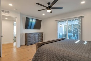 A bedroom with a bed, a ceiling fan, a TV, and a sliding glass door leading to a balcony. - Perfect for Families! Private Pool, Spa & BBQ, Near Shopping, Dining, Mayo Clinic + Free Golf (Phoenix)