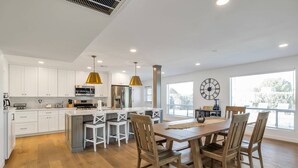 Una cocina moderna con armarios blancos, electrodomésticos de acero inoxidable y una isla grande con taburetes de bar.