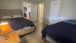 Hotellihuone, jossa on kaksi sänkyä, kattotuuletin, lamppu ja pieni pöytä.
