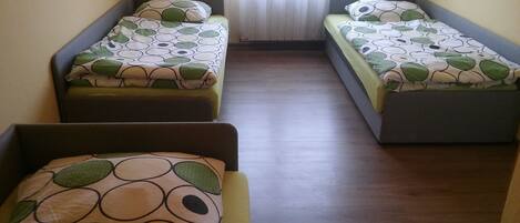 Una habitación con tres camas individuales dispuestas en fila, cada una con una colcha estampada y almohadas a juego.