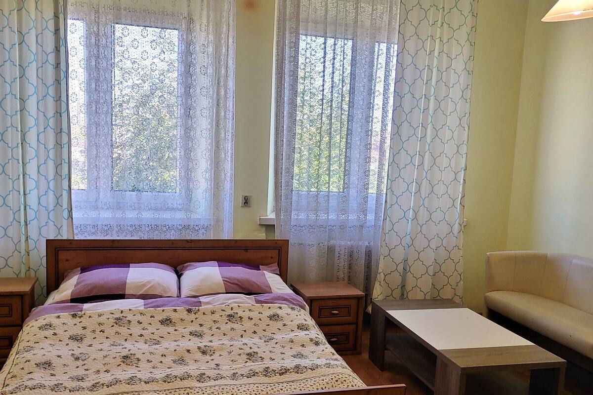 Ein Schlafzimmer mit einem Bett, einem Nachttisch, einem Sessel und einem kleinen Tisch.