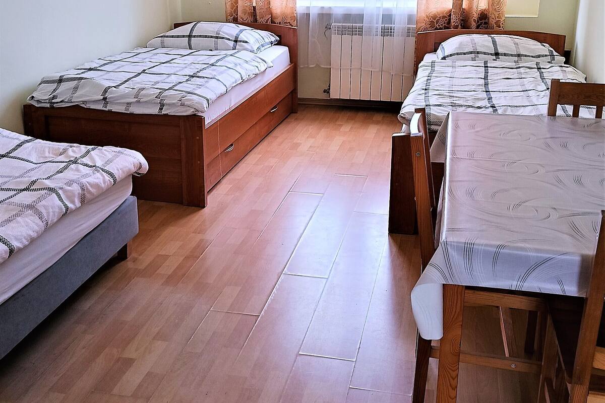 Ein Zimmer mit zwei Einzelbetten, einem Tisch mit Stühlen und einer Heizung.