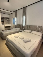 Habitación triple, balcón | Tabla de planchar con plancha y ropa de cama