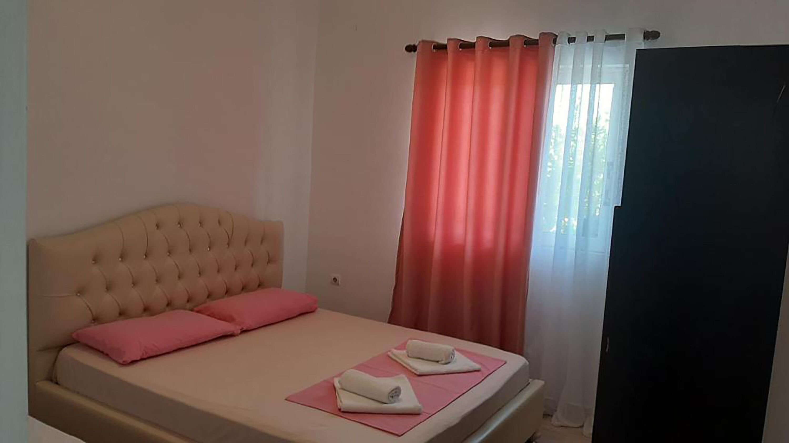 Ein Schlafzimmer mit einer gesteppten Kopfteile, einem Bett mit rosa Bettwäsche und zwei Handtüchern auf rosa Matten.