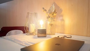 A laptop on a bed with a candle and decorative items in the background. - LaOla Living - Hostel (Essen)
