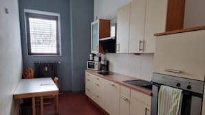 A compact kitchen with a dining table, a built-in microwave, a coffee maker, and a stove. - LaOla Living - Hostel (Essen)