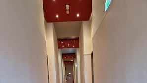A long, narrow hallway with a red carpet and white walls. - LaOla Living - Hostel (Essen)