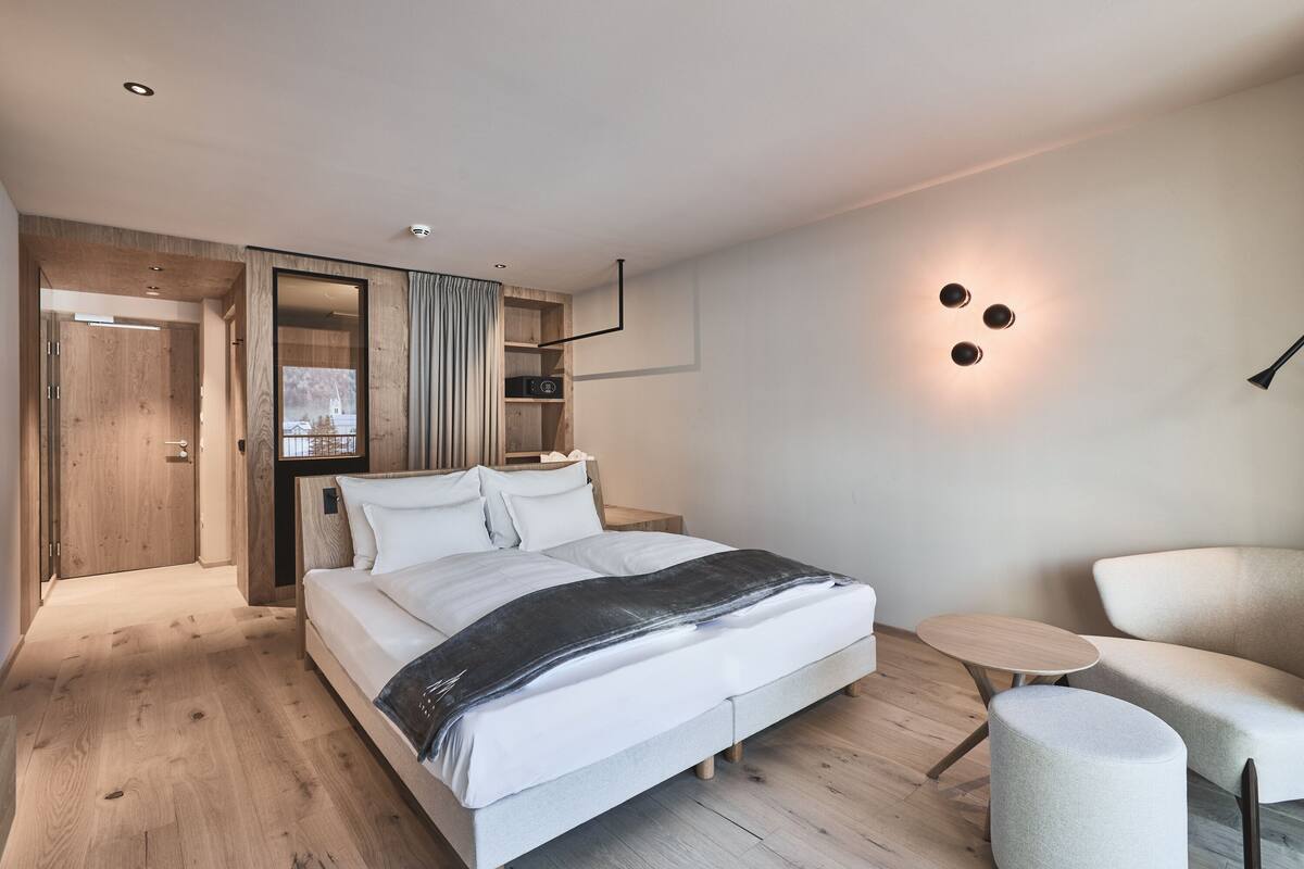 Ein modernes Schlafzimmer mit einem großen Bett, einem Nachttisch, einem Sessel und einem Einbauschrank.